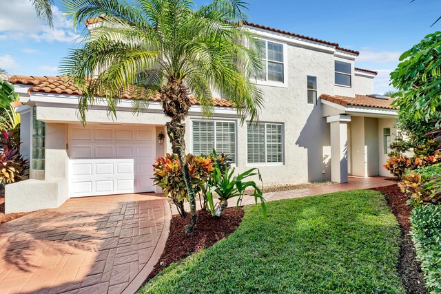 mediterranean / spanish house with a garage and a front lawn