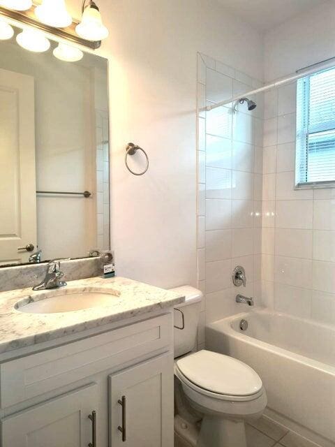 full bathroom featuring vanity, tiled shower / bath combo, toilet, and tile patterned flooring