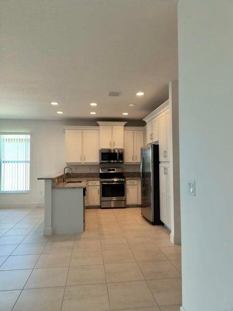 kitchen with white cabinets, light tile patterned flooring, sink, and stainless steel appliances