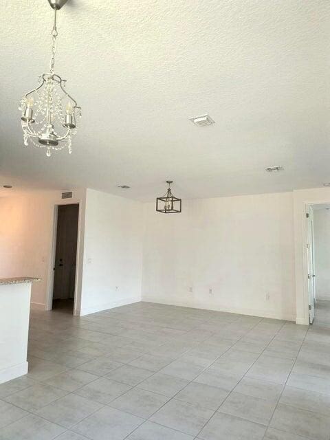 unfurnished room featuring a chandelier and a textured ceiling