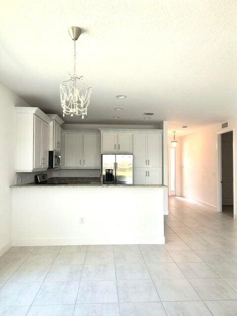 kitchen with white cabinetry, stainless steel appliances, a notable chandelier, pendant lighting, and light tile patterned flooring