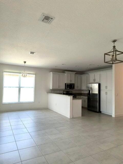 kitchen with white cabinetry, hanging light fixtures, a textured ceiling, and appliances with stainless steel finishes