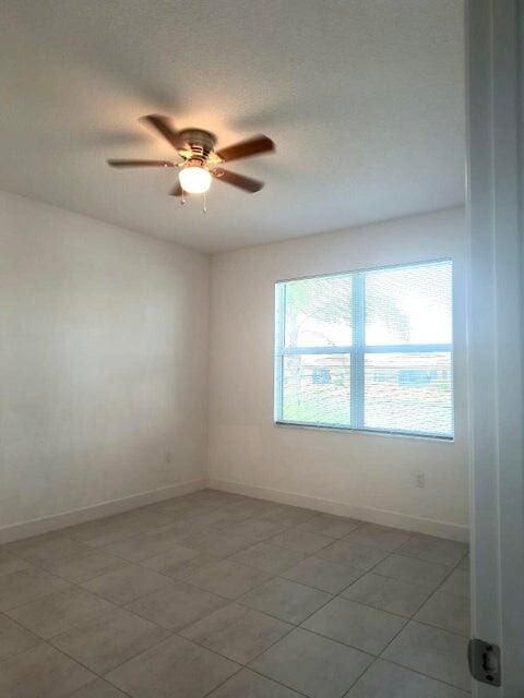 unfurnished room with ceiling fan and a textured ceiling