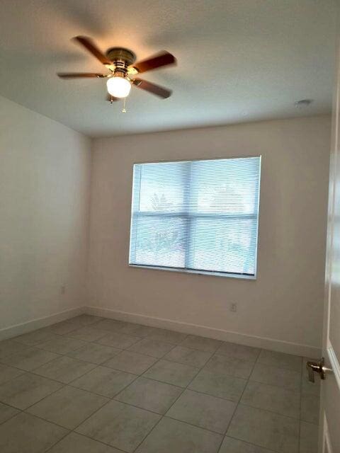 tiled spare room with ceiling fan