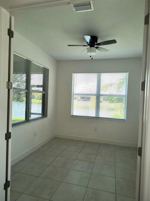 tiled spare room with ceiling fan and a textured ceiling