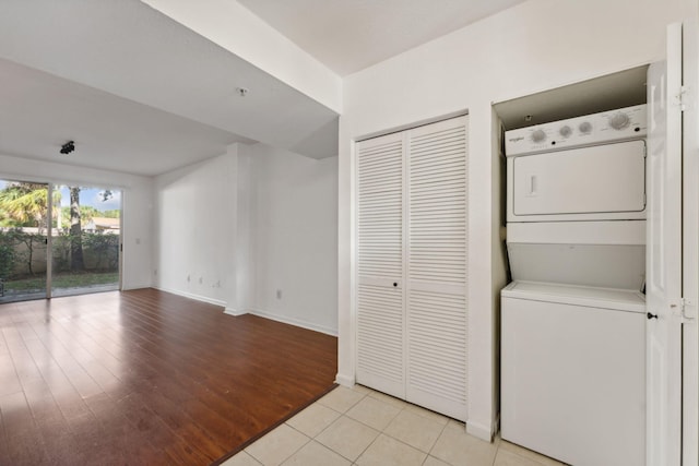 laundry room featuring stacked washer and dryer and light wood-type flooring