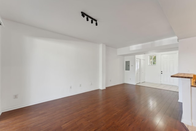 unfurnished living room featuring wood-type flooring, rail lighting, and electric panel