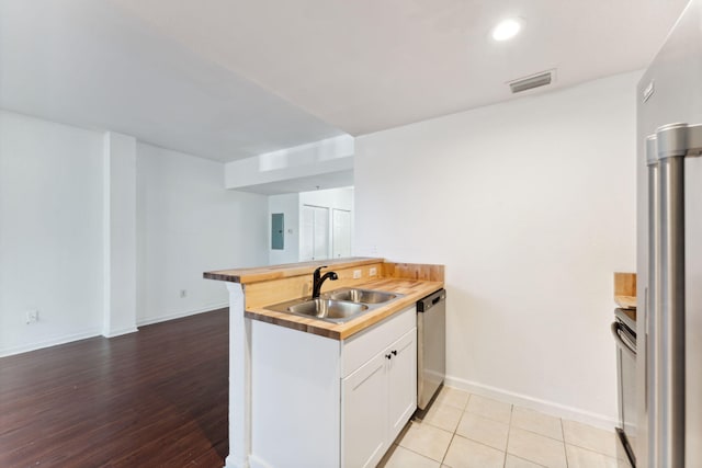 kitchen featuring light tile patterned flooring, dishwasher, sink, white cabinets, and kitchen peninsula