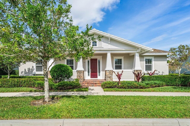 view of front facade with a front yard, stone siding, and stucco siding