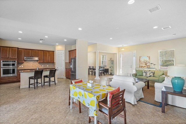 living area featuring ornate columns, visible vents, a textured ceiling, and recessed lighting