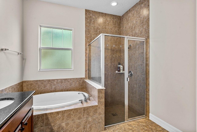 full bath with a textured ceiling, vanity, baseboards, a shower stall, and a bath