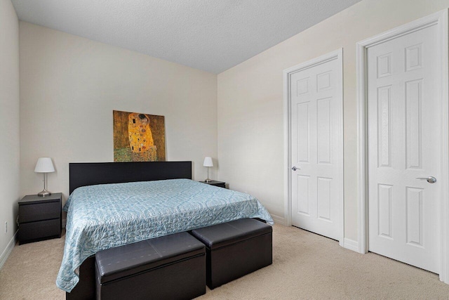 bedroom with light colored carpet and a textured ceiling