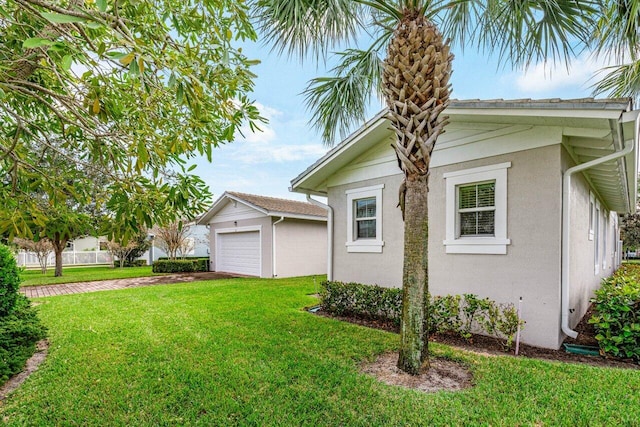 view of home's exterior featuring a lawn, a detached garage, and stucco siding