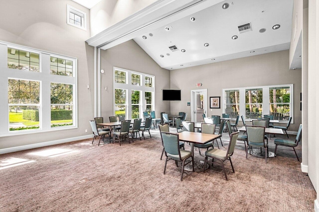 carpeted dining area featuring a towering ceiling