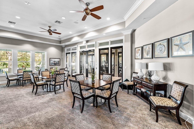 carpeted dining room featuring ceiling fan, ornamental molding, a tray ceiling, and decorative columns