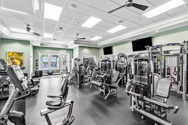 exercise room with a paneled ceiling, ornamental molding, a raised ceiling, and ceiling fan