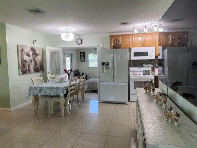 kitchen featuring a notable chandelier, white appliances, backsplash, and light tile patterned floors