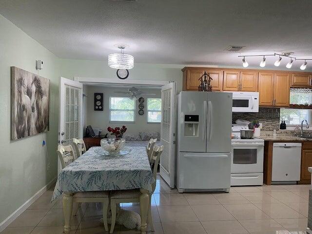 kitchen featuring sink, white appliances, an inviting chandelier, and light tile patterned flooring