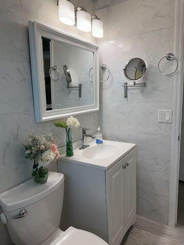 bathroom with vanity, toilet, and tile walls