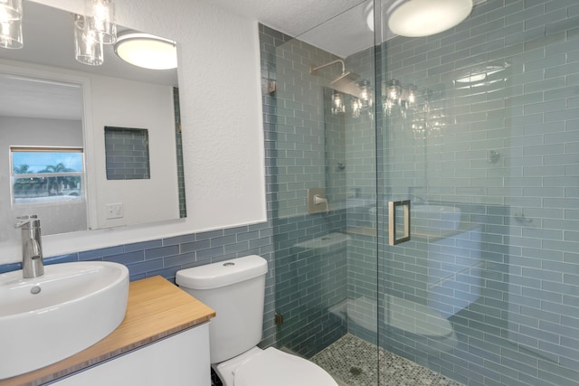 bathroom featuring vanity, toilet, a shower with door, and tile walls