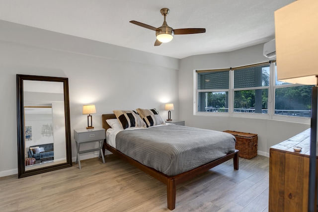 bedroom featuring ceiling fan, light wood-type flooring, and a wall mounted AC