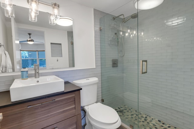 bathroom with vanity, toilet, a shower with shower door, and tile walls