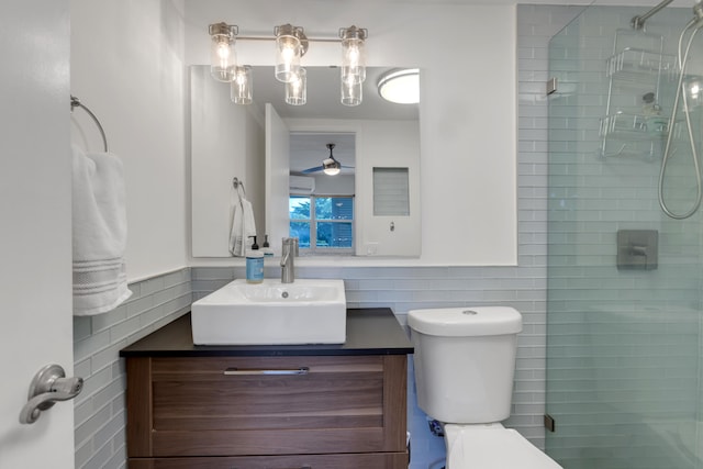 bathroom with a shower with door, vanity, tile walls, and toilet