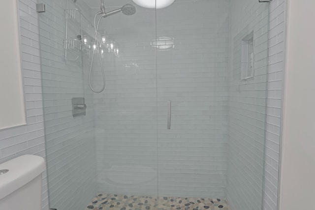 bathroom featuring a shower with shower door and toilet