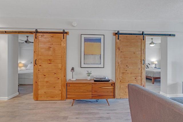 bedroom with a barn door and light wood-type flooring