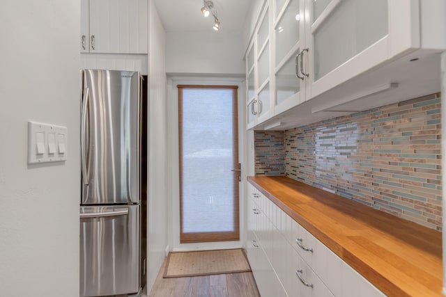 kitchen featuring stainless steel refrigerator, wood counters, tasteful backsplash, light hardwood / wood-style floors, and white cabinets