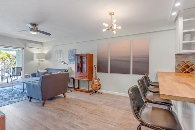 living room with ceiling fan with notable chandelier, light hardwood / wood-style floors, and a wall unit AC