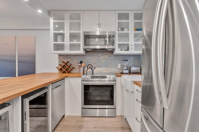 kitchen featuring white cabinets, light hardwood / wood-style flooring, appliances with stainless steel finishes, butcher block counters, and beverage cooler