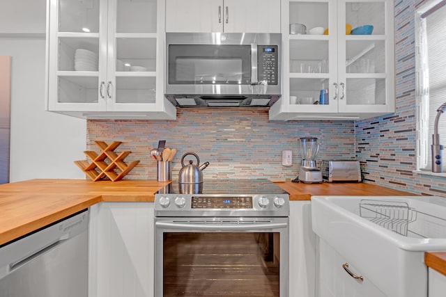 kitchen with decorative backsplash, stainless steel appliances, white cabinets, and wood counters