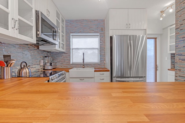 kitchen with tasteful backsplash, sink, white cabinets, and appliances with stainless steel finishes