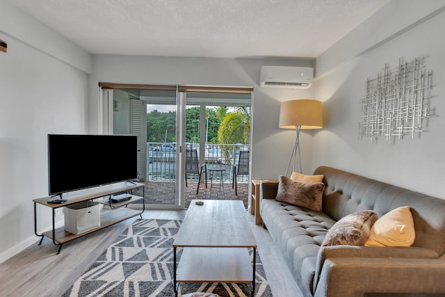 living room with a textured ceiling, a wall mounted air conditioner, and light wood-type flooring