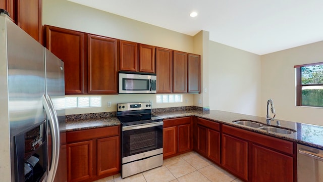 kitchen featuring sink, stainless steel appliances, kitchen peninsula, dark stone countertops, and light tile patterned floors