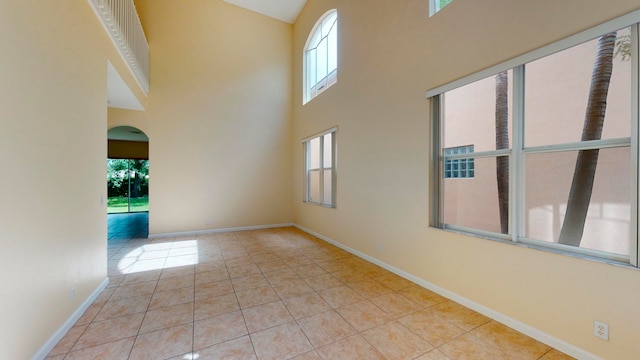 tiled spare room with plenty of natural light and a towering ceiling