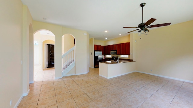 kitchen with ceiling fan, sink, stainless steel appliances, kitchen peninsula, and light tile patterned flooring