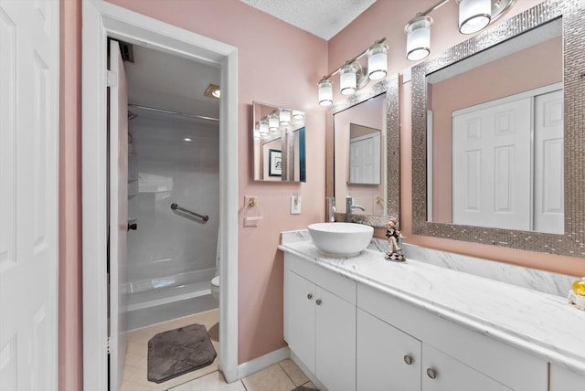 bathroom with tile patterned flooring, vanity, a textured ceiling, and walk in shower