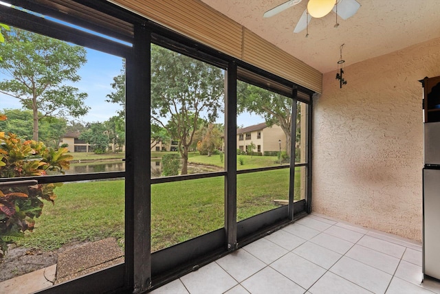 unfurnished sunroom featuring plenty of natural light, ceiling fan, and a water view