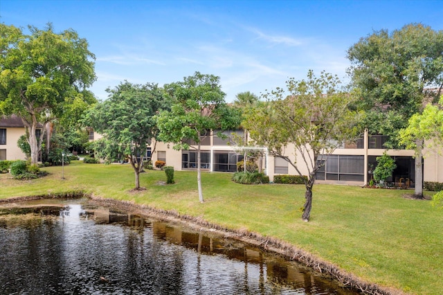 back of property featuring a water view and a lawn