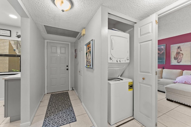 washroom featuring light tile patterned floors, a textured ceiling, and stacked washer / dryer