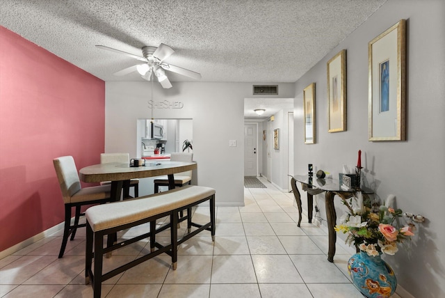 tiled dining room featuring ceiling fan and a textured ceiling