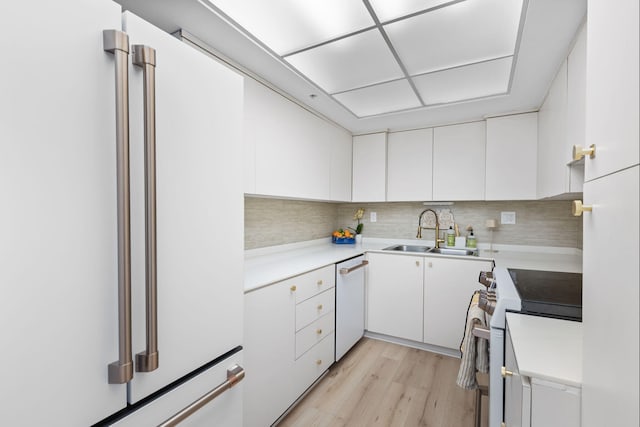 kitchen featuring sink, tasteful backsplash, white appliances, white cabinets, and light wood-type flooring