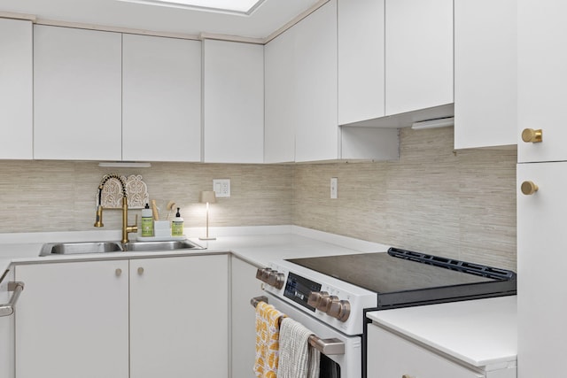 kitchen with decorative backsplash, white cabinetry, sink, and stainless steel range