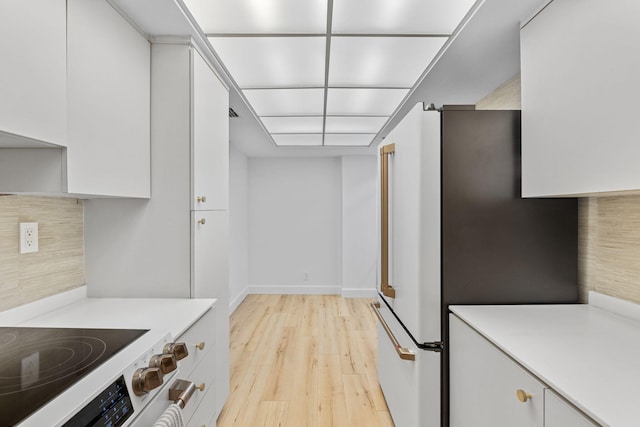 kitchen with decorative backsplash, stainless steel fridge, light wood-type flooring, and white cabinetry