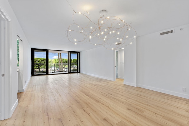 unfurnished living room featuring floor to ceiling windows, a chandelier, and light wood-type flooring