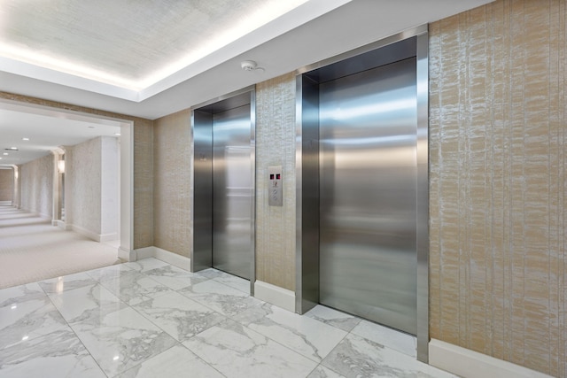 interior space featuring a raised ceiling and elevator