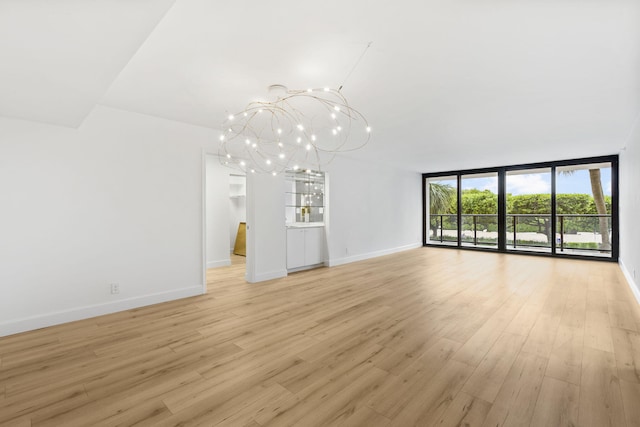 unfurnished living room with a wall of windows, light hardwood / wood-style flooring, and a notable chandelier