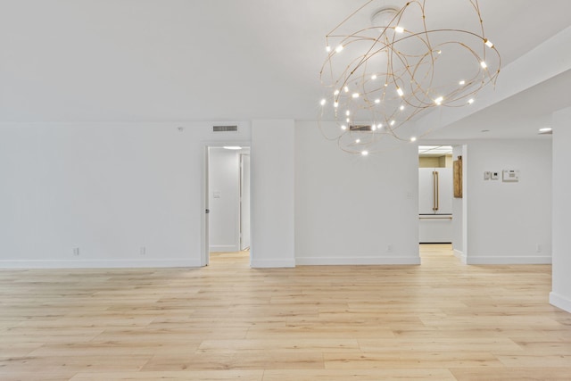 spare room with light hardwood / wood-style flooring and an inviting chandelier